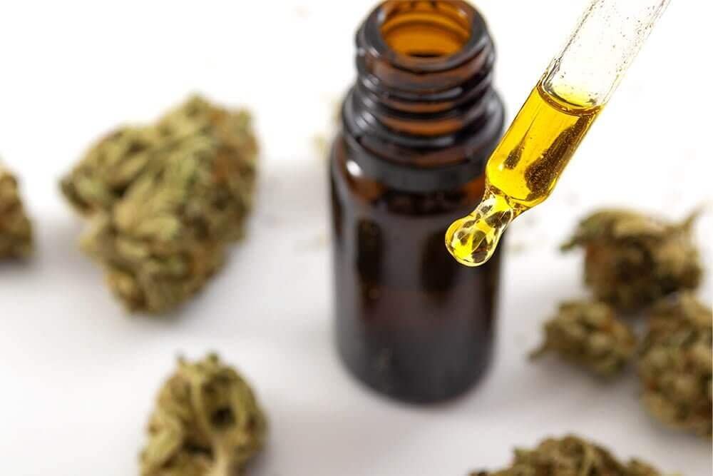 Two cannabis tincture bottles on a wooden surface, one alcohol-based and one oil-based, illustrating the difference between extraction solvents