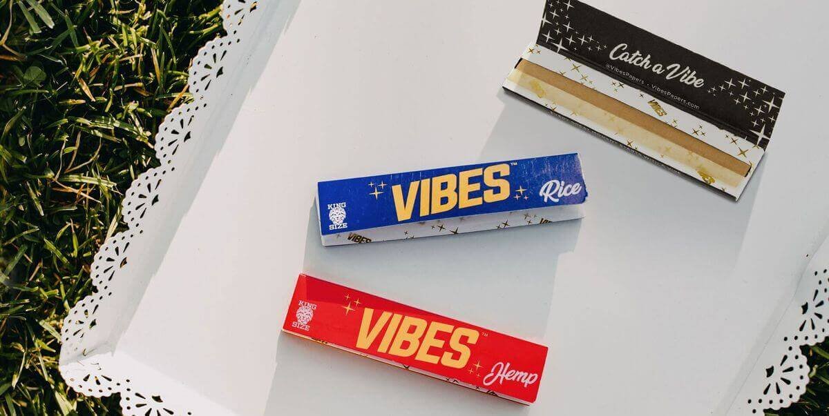 VIBES Rice and VIBES Hemp rolling paper booklets with an open paper booklet on a white tray