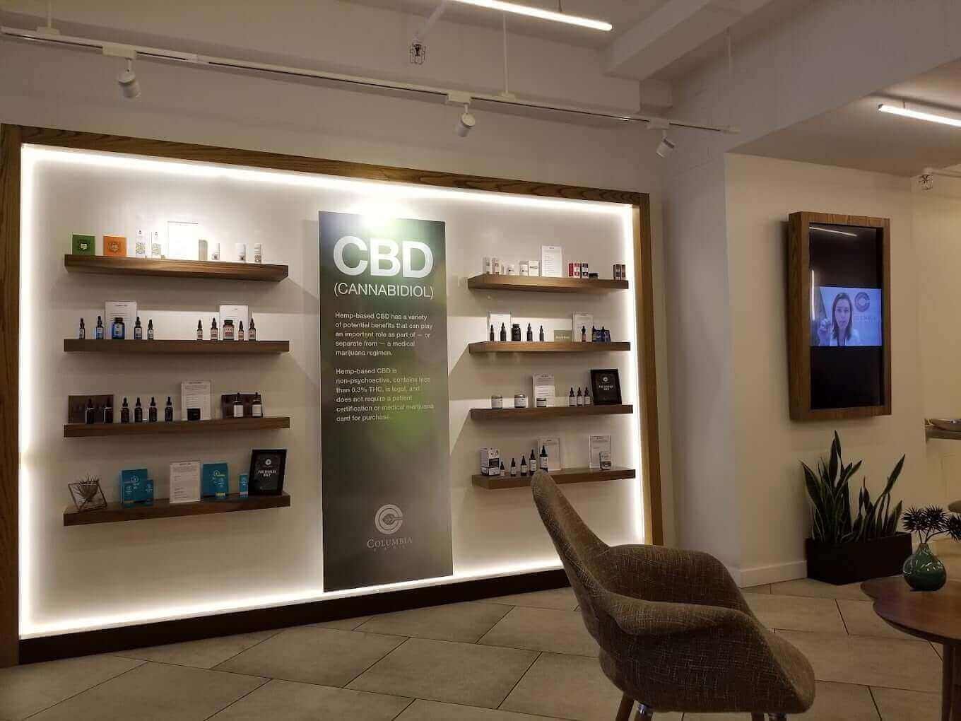 CBD product wall display with illuminated wooden shelves and central green informational banner