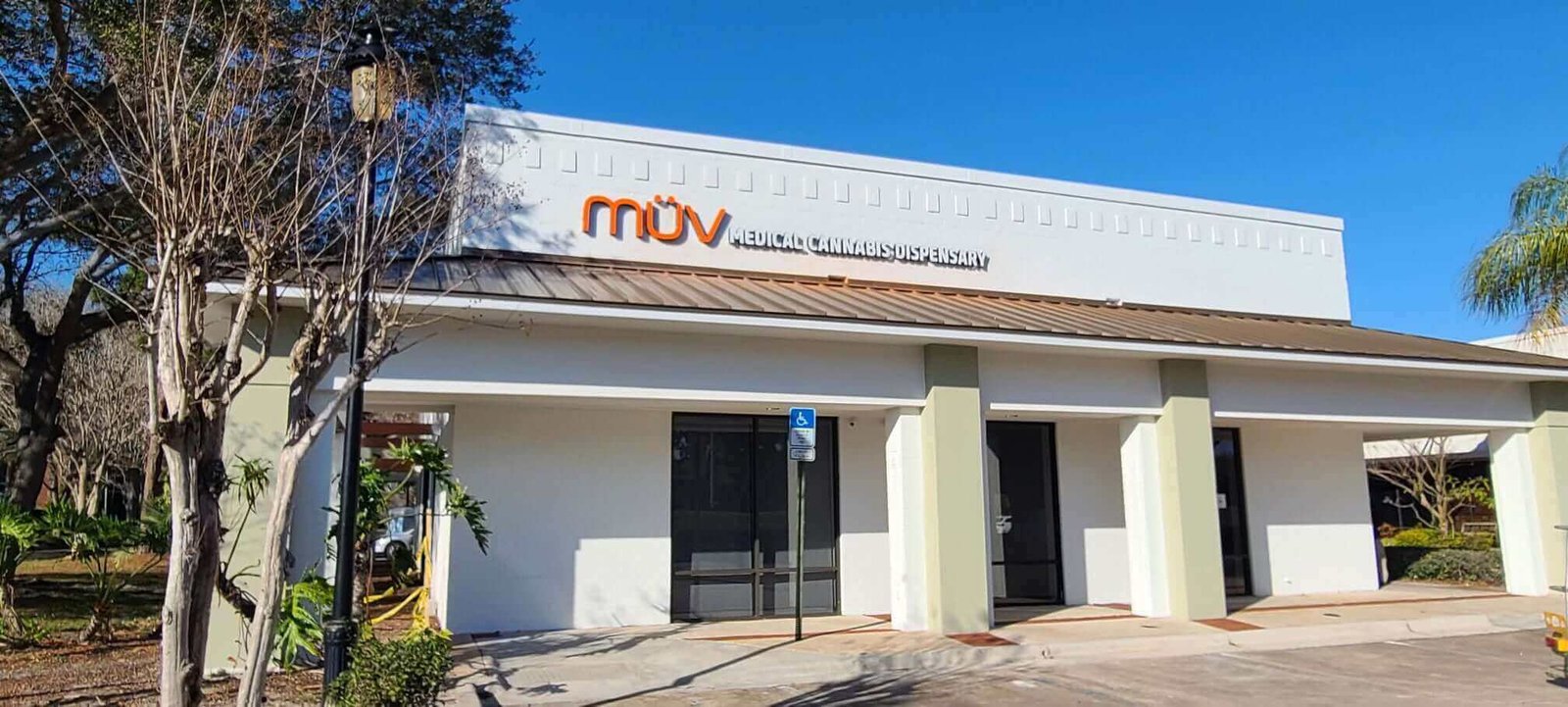 Exterior of MUV medical cannabis dispensary storefront on sunny day with palm trees and clear sky