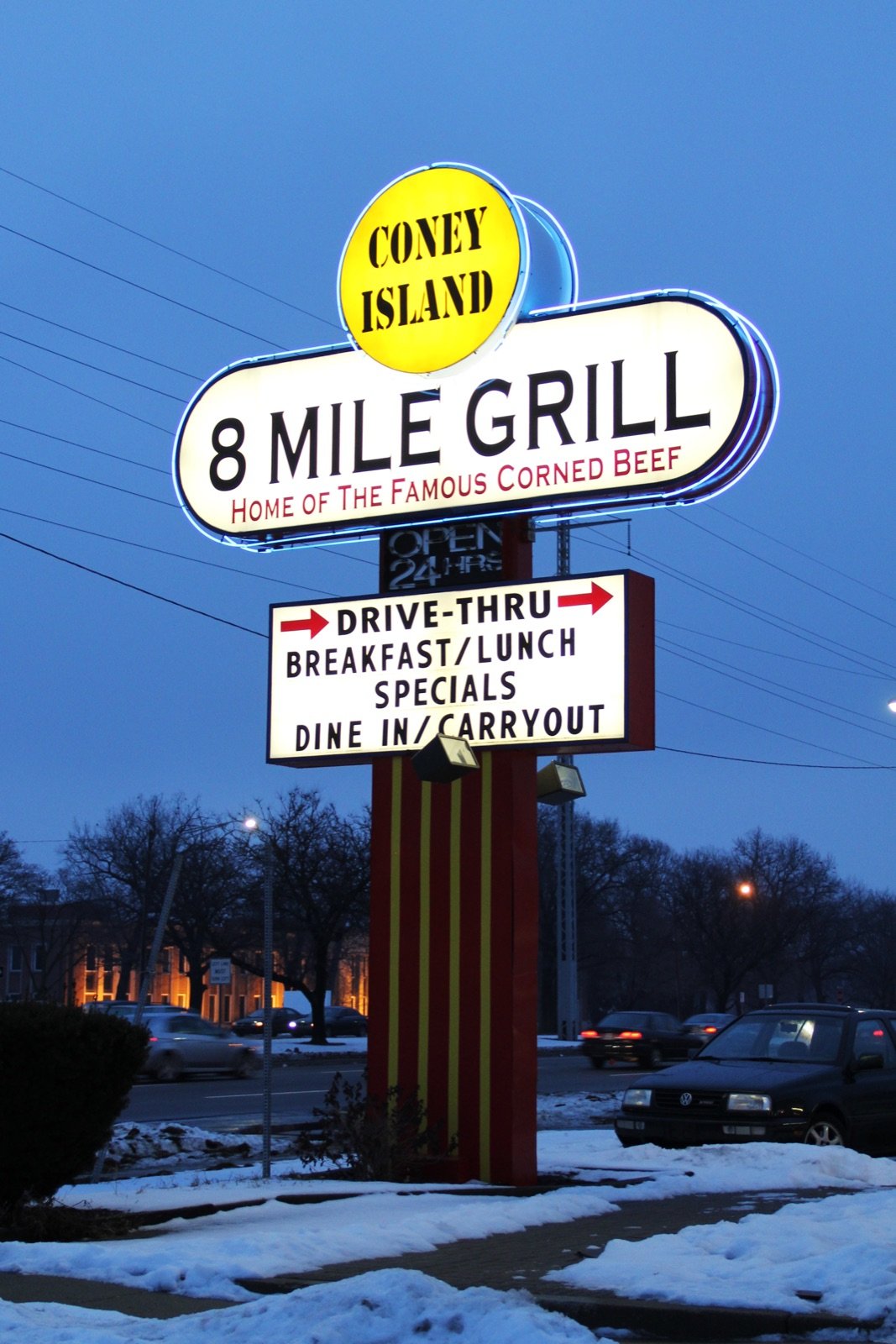 Vintage 8 Mile Grill Coney Island neon drive-thru sign at dusk on 8 Mile Road in Detroit advertising corned beef breakfast and dine-in carryout