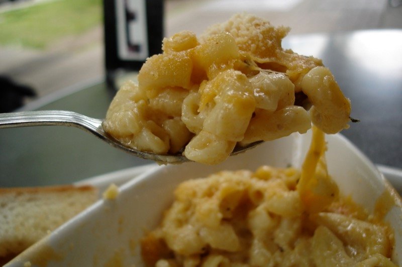 Spoonful of golden baked macaroni and cheese with browned crust lifted from the dish