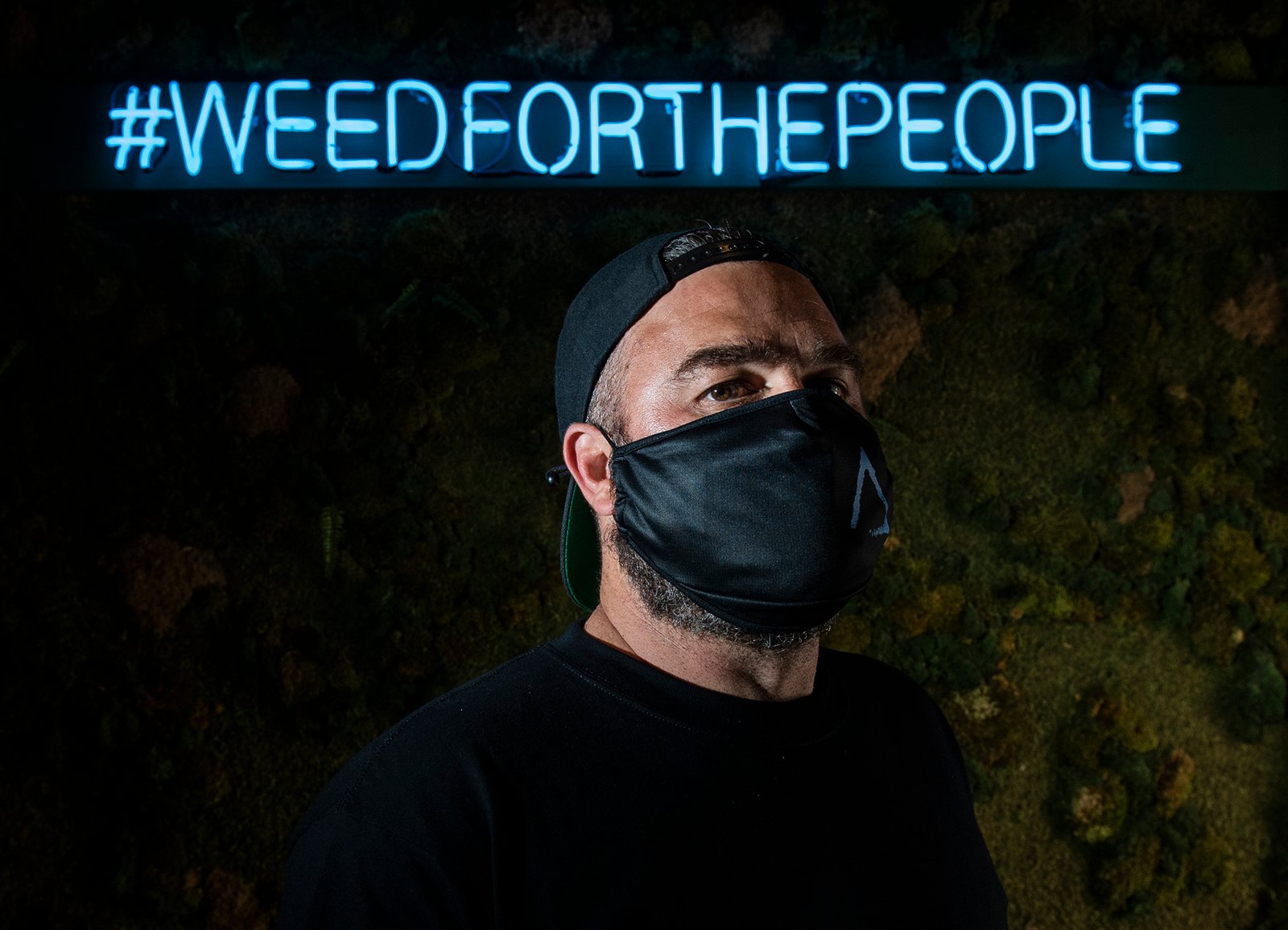 Catalyst Cannabis founder Elliot Lewis inside a Long Beach Catalyst store under the brand's Weed For The People neon