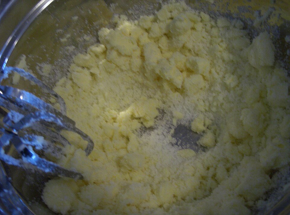 Cannabutter being creamed with brown and white sugar in a stand mixer bowl until light and fluffy, the first step in cannabis chocolate chip cookies