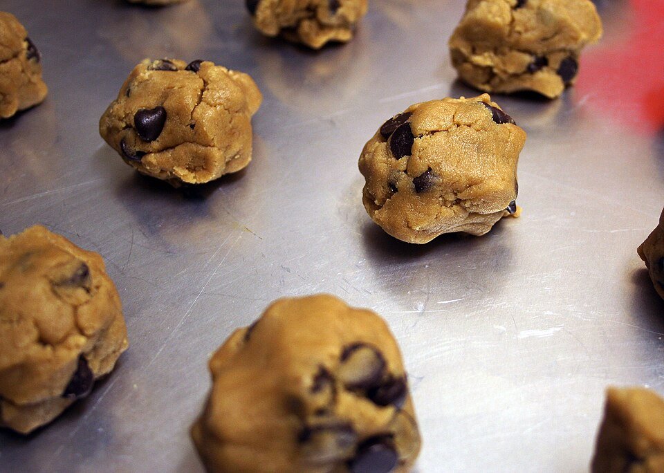 Tablespoon-sized cannabis cookie dough balls scooped onto a parchment-lined baking sheet, spaced two inches apart, ready for a 350F oven