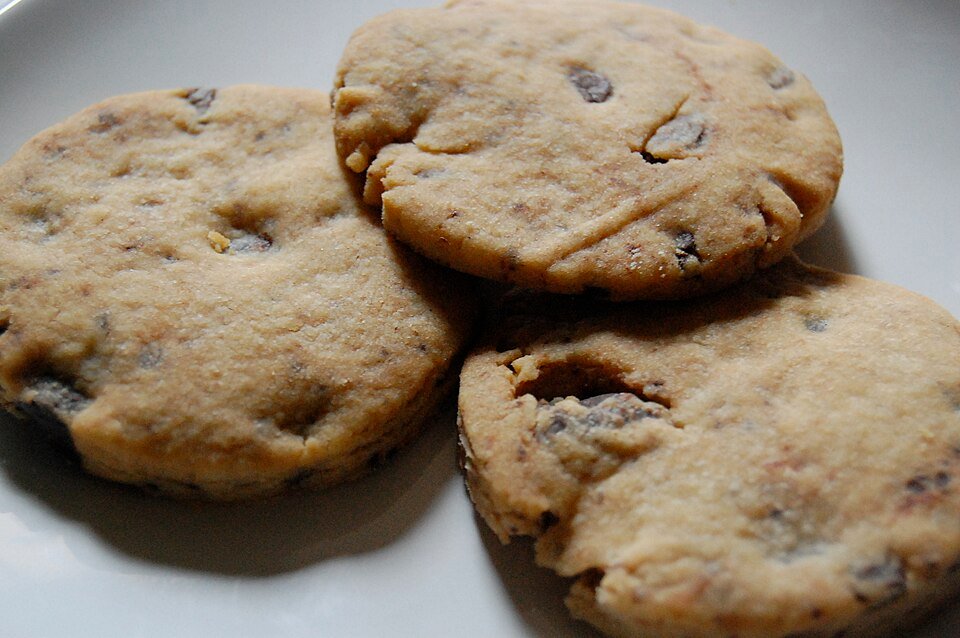 Finished cannabis chocolate chip cookies cooling on a baking sheet straight out of the oven, edges set and centers still soft