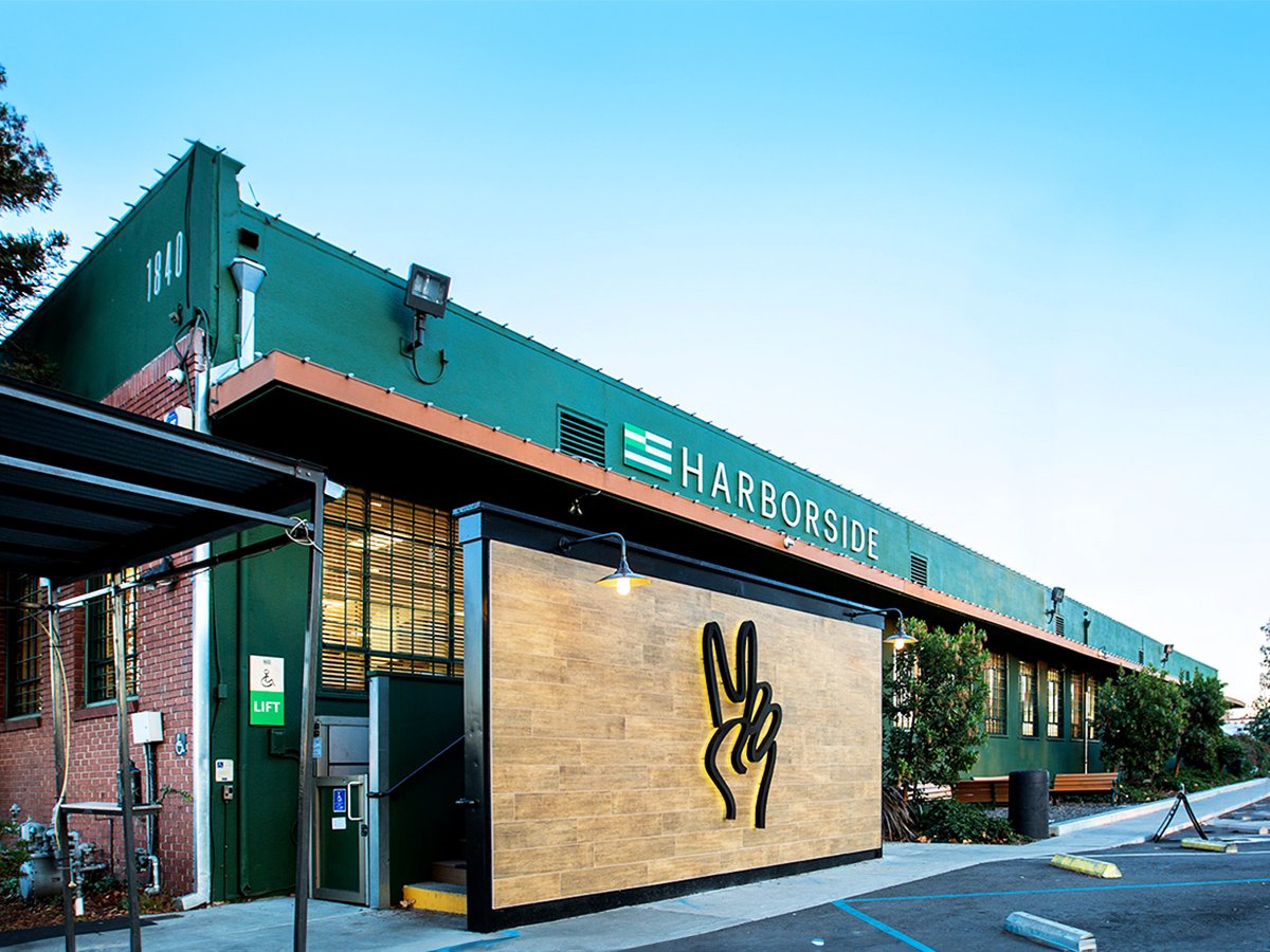 Harborside Oakland exterior at 1840 Embarcadero with the dispensary's peace-fingers logo on the sign