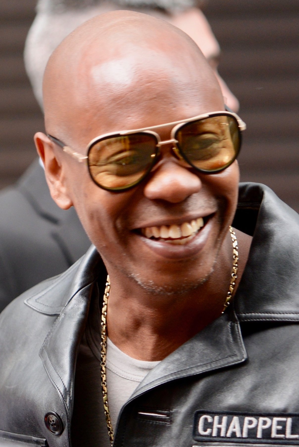 Stand-up comedian Dave Chappelle in his signature CHAPPELLE leather jacket and aviator sunglasses, the cowriter of Half Baked and most argued-about working stoner comic.