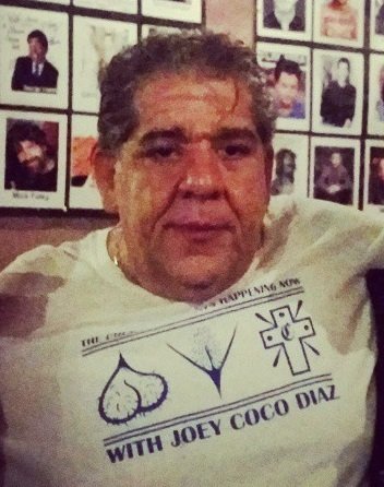 Stand-up comedian Joey Coco Diaz wearing a Joey Coco Diaz t-shirt, the cannabis patriarch of late-era stand-up and longtime podcast staple.