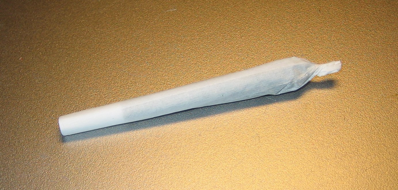 Hand-rolled cannabis joint with rolling paper and twisted tip on a tan surface, representative of the pre-roll category Curaleaf Illinois carries through its Weed Street and Skokie dispensary footprint built on the 2020 Grassroots Cannabis acquisition