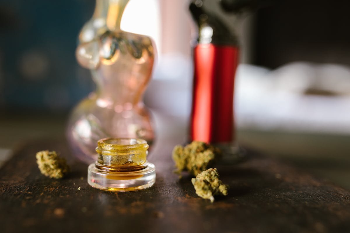 Cannabis live rosin concentrate in a small glass concentrate jar with cannabis flower buds and dab rig, representative of the Lazercat ice water hash and live rosin program processed at 10,000 feet in the Colorado mountains