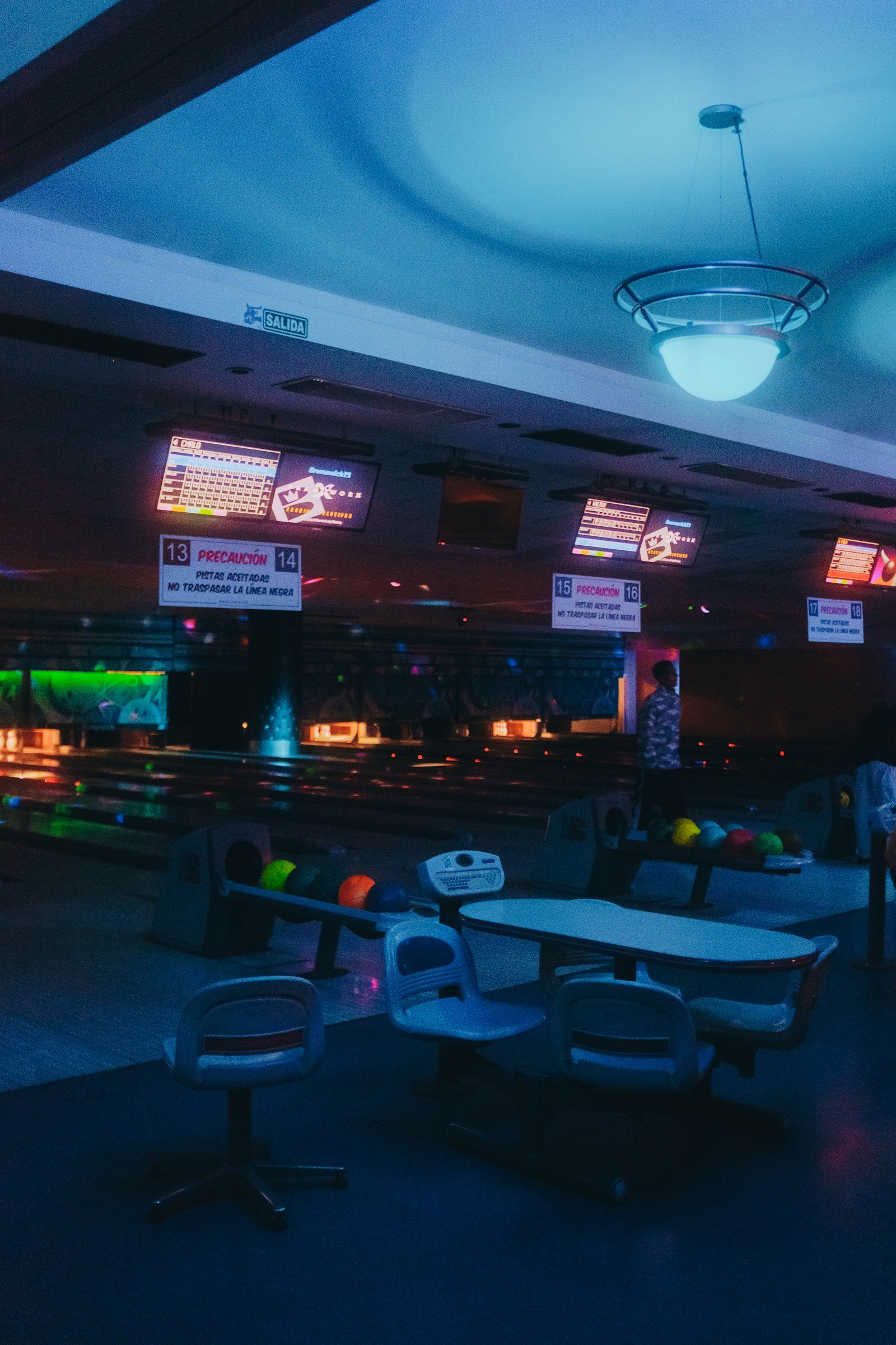 Empty bowling alley with neon scoring screens evoking the league night setting central to The Big Lebowski