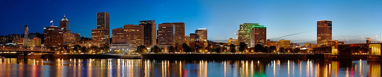 Portland downtown skyline at dusk with waterfront bridges reflecting colored lights on Willamette River