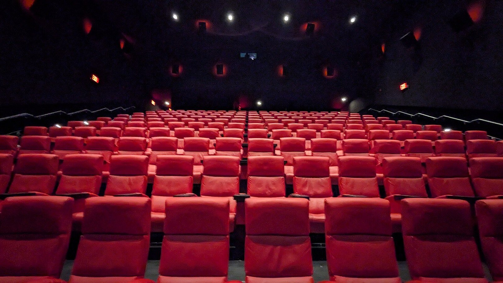 Empty movie theater seats lit in red, illustrating the home theater vibe of a stoner movie night