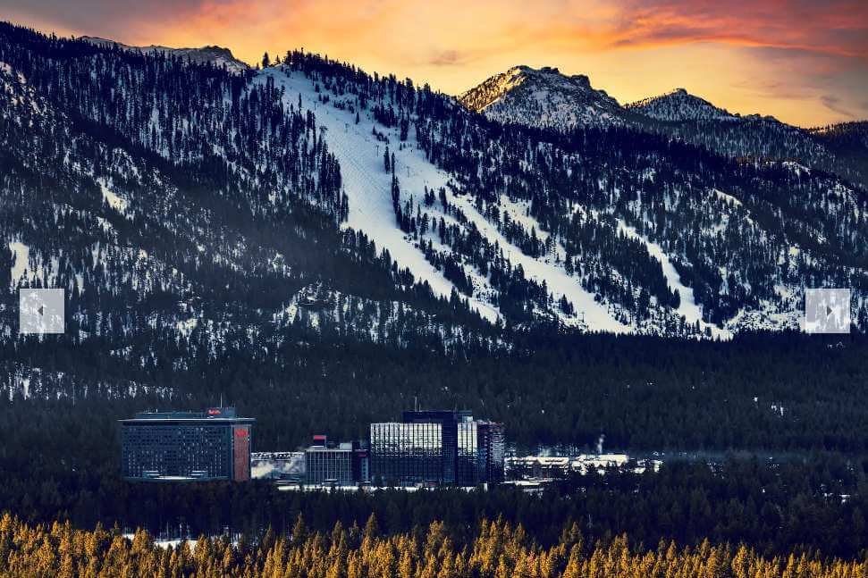 Stateline Nevada casino corridor at sunset with Heavenly Mountain ski runs lit behind the resorts