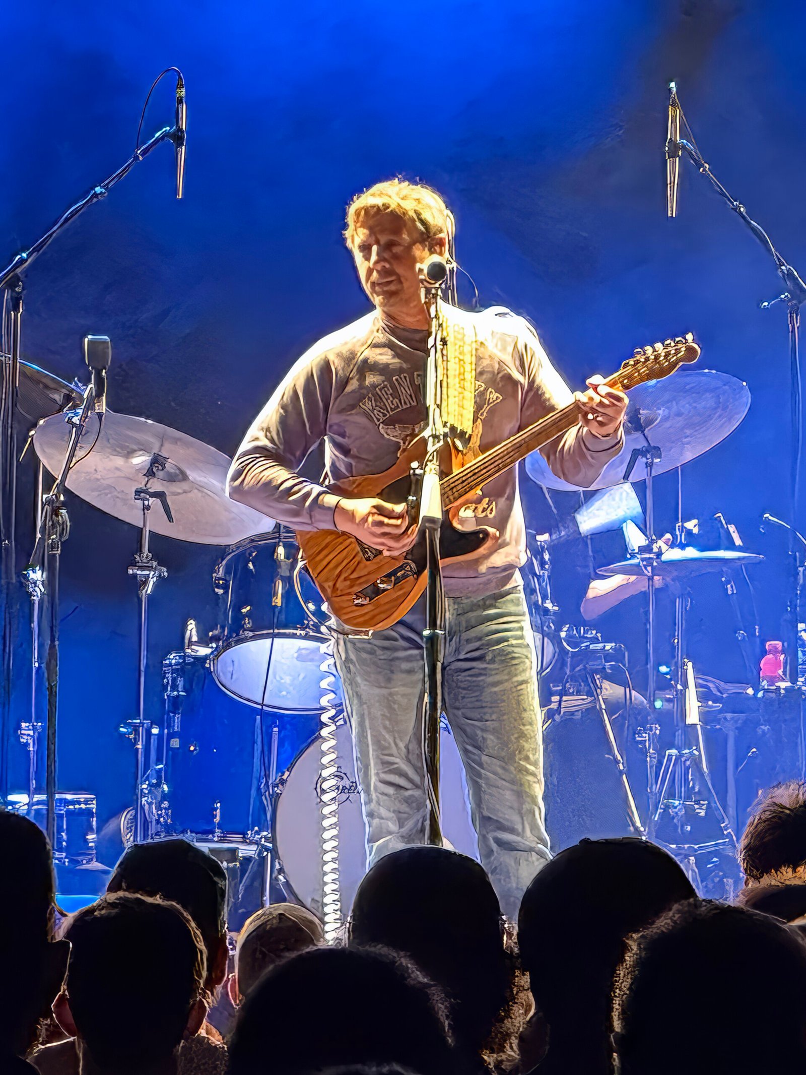 Sturgill Simpson performing as his Johnny Blue Skies stage persona with a bass guitar under blue stage lights, the Kentucky songwriter who put DMT and marijuana into the same verse on Turtles All the Way Down in 2014