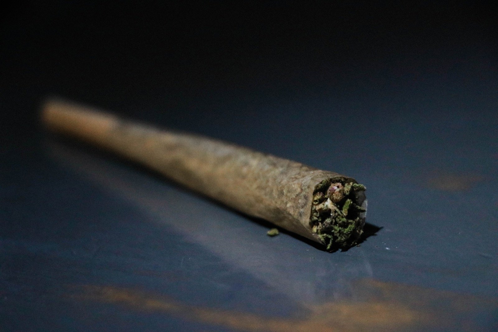 A burning cannabis pre-roll resting on a dark surface, the kind of single-serve format Torrey Holistics keeps below ten dollars on the menu