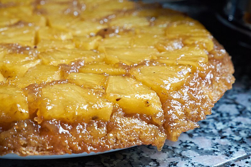 Golden pineapple upside-down cake on a white plate with caramelized pineapple ring tops and a cherry in the center, the hero recipe for a Pineapple Express movie night