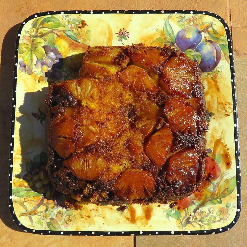 A single slice of pineapple upside-down cake on a plate showing the moist crumb and amber pineapple ring on top, the per-portion serving for cannabis dosing math