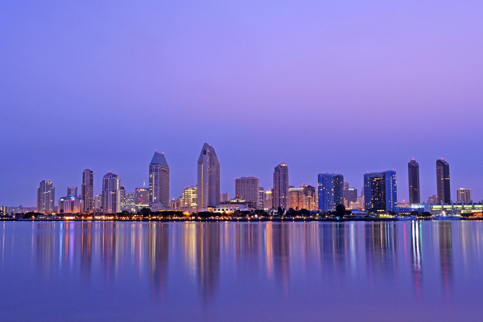 San Diego downtown skyline reflecting in San Diego Bay at dawn, with Coronado in the foreground