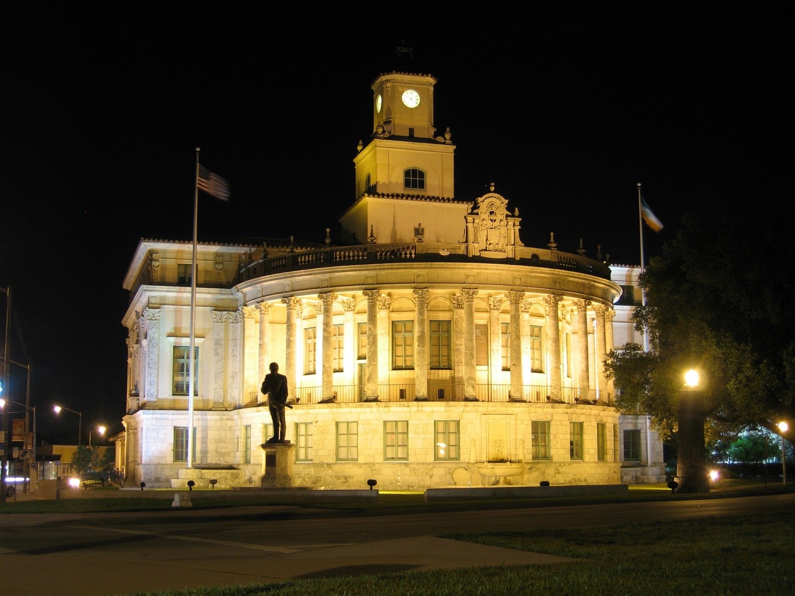 Coral Gables City Hall lit up at night with the clock tower and Florida flags out front