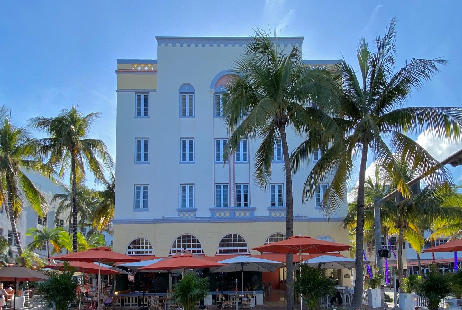 Art Deco hotel facade on Ocean Drive in South Beach Miami Beach with palms and red cafe umbrellas