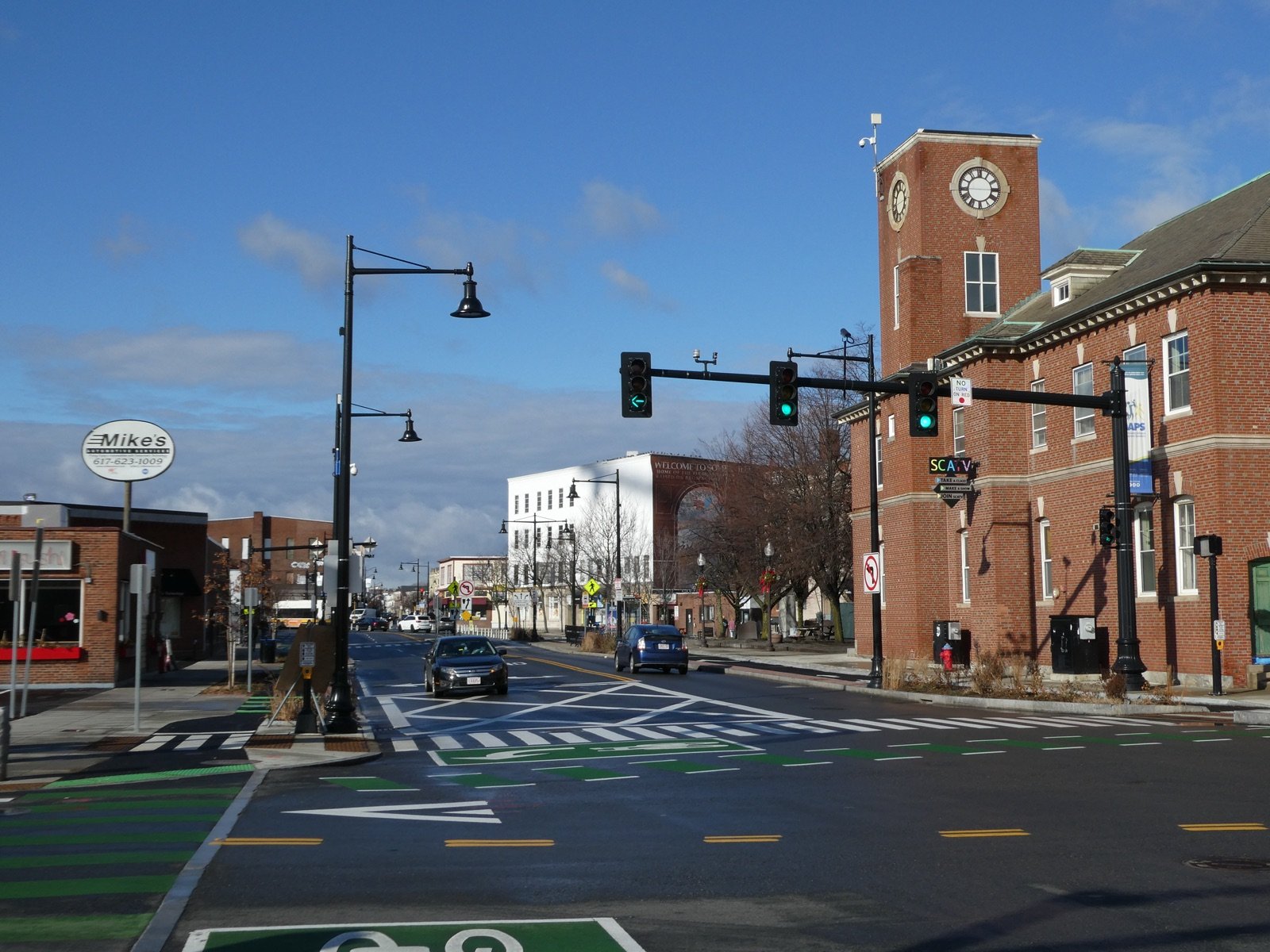 Union Square Somerville Massachusetts with the historic Somerville Avenue clock tower and Welcome to Union Square mural at the intersection near Cookies dispensary