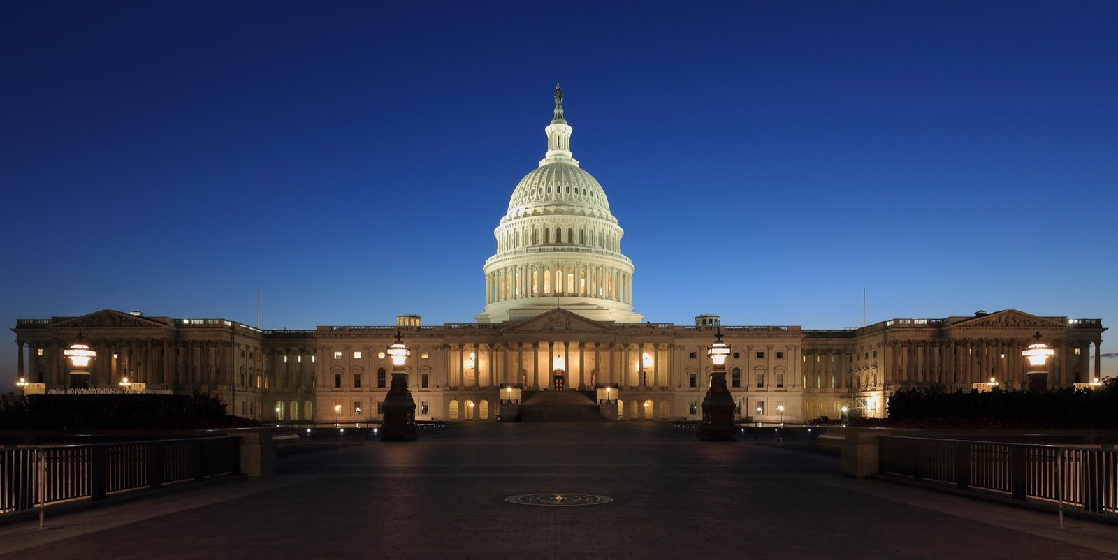 United States Capitol building at dusk in Washington DC with the dome lit and the National Mall in the foreground